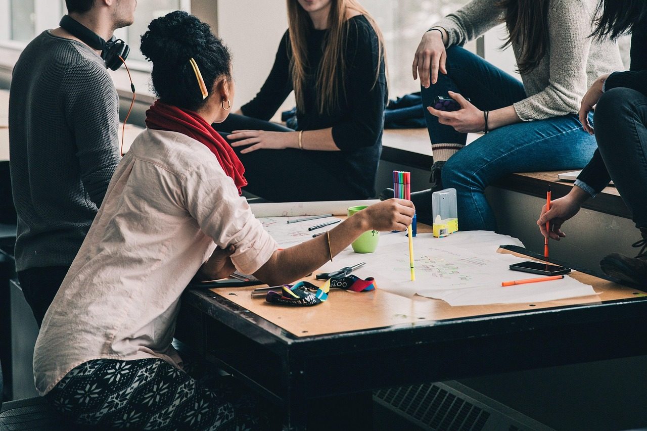 Schüler:innen arbeiten in einer Gruppe gemeinsam an einem Tisch